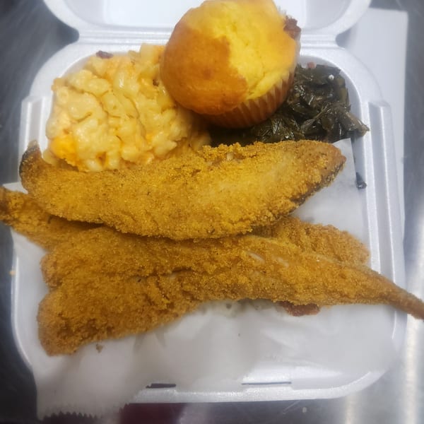 Soul food meal with fried fish, macaroni and cheese, collard greens, and a cornbread muffin.