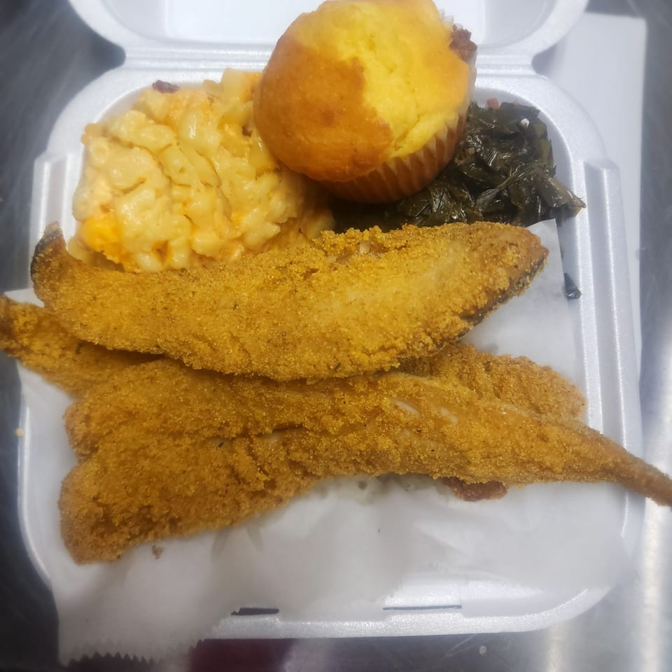 Soul food meal with fried fish, macaroni and cheese, collard greens, and a cornbread muffin.